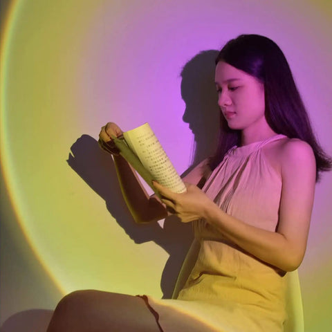 Woman reading under sunset projection from Sunset Projection Lamp 6W LED With 180 Degree Rotating Head, Wireless App Control And Remote.