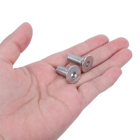Hand holding two Flat Head Hex Socket Screws Full Thread M8x60mm Stainless Steel for furniture and cabinet assembly.