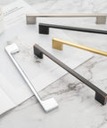 Wide Foot Cabinet Bar Pull In Matte Black 5 Inch 128mm Screw Spacing Solid Metal Hardware, shown with other finishes on marble surface