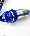 Close-up of Blue Aluminum BigBore Shocks for 4x4 and 2WD Trucks, showing spring and adjustment dial, high performance suspension upgrade.