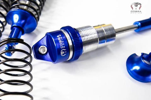 Close-up of Blue Aluminum BigBore Shocks for 4x4 and 2WD Trucks, showing spring and adjustment dial, high performance suspension upgrade.
