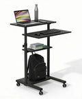 Black Rolling Standing Desk With Adjustable Height Up To 54.7 Inches, showing laptop, keyboard, shelves, and backpack