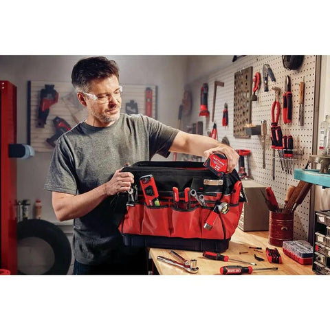 VersaStack Zippered Tool Bag With 31 Pocket Organizer held by man in workshop, showcasing durable 1680 denier fabric and tools.