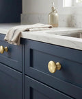 Champagne Bronze Cabinet Knobs Set of 25 on blue drawers with marble countertop.