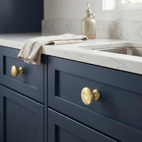 Champagne Bronze Cabinet Knobs Set of 25 on blue drawers with marble countertop.