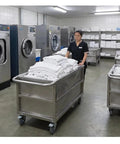 Industrial Stainless Steel Utility Cart With Locking Swivel Wheels And Deep Soak Tank for hauling linens in a laundry room.