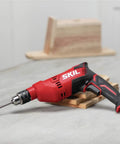 Powerful 7.5 Amp Corded Drill With Half Inch Heavy Duty Keyed Chuck Side Assist Handle For Better Control Two Finger Variable Speed Trigger And Built In Horizontal Bubble Level For Precise Drilling resting on a table.