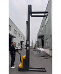 Heavy Duty Electric Pallet Stacker Battery Powered Hydraulic Lift Truck in warehouse lifting pallets up high.