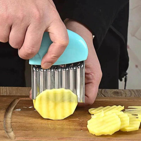 Front view of blue plastic-handled stainless steel crinkle cutter slicing a potato on a cutting board.