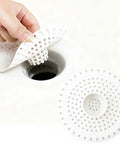 Universal Five Inch Silicone Shower Drain Hair Catcher being lifted from a drain, blocking hair and debris in a bathroom sink.