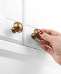 Hand installing Ten Pack One And One Quarter Inch Antique Brass Kitchen Cabinet Knobs For Cabinets Drawers Dresser Cupboard Bedroom And Bathroom Hardware Real Solid Metal Vintage Brass Knob Set With Classic Look Built To Last on white cabinet.