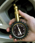 JACO Elite Low Pressure Tire Gauge close-up showing brass connector attached to tire valve on a car wheel