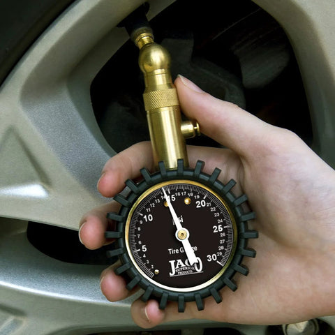 JACO Elite Low Pressure Tire Gauge close-up showing brass connector attached to tire valve on a car wheel
