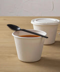 Six Point Five Inch Wrapped Compostable Spoons For Hot And Cold Food 250 Individually Wrapped Plant Based Black CPLA Disposable Utensils BPI Certified Eco Friendly Cutlery For Restaurants And Events black CPLA spoon over soup cup