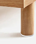 Close-up of a wooden table leg with a Rock Solid White Furniture Levelers 16 Pack M6 X 18mm Thread Table Leg Adjustable Feet 23mm Base.