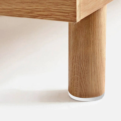 Close-up of a wooden table leg with a Rock Solid White Furniture Levelers 16 Pack M6 X 18mm Thread Table Leg Adjustable Feet 23mm Base.
