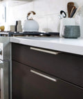 Emtek Edge 8 Inch Center To Center Finger Cabinet Pull 87130US4 installed on modern kitchen drawers, sleek design