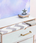 Open drawer with antique brass cabinet handle, featuring chevron-patterned blanket and decorative items on top, showcasing usage.