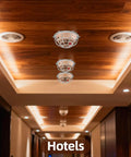 Heavy Duty Metal Detector Guard Cover And Fire Alarm Protector With Tool Less Quick Mount For Sprinkler Heads And Smoke Sensors In Homes Offices Hotels Garages And Commercial Buildings Built Tough To Keep Things Secure mounted on ceiling in hotel corridor.