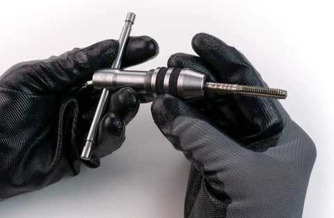 Two Piece Tap Wrench Set with Sliding T Handle and Reference Table for Zero to One Half Inch Taps held in gloved hands