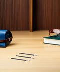 Ten Pairs Glasses Arm Replacement Kit With Metal Temple Tips, showing anti slip eyewear grips near case and book on wooden table.