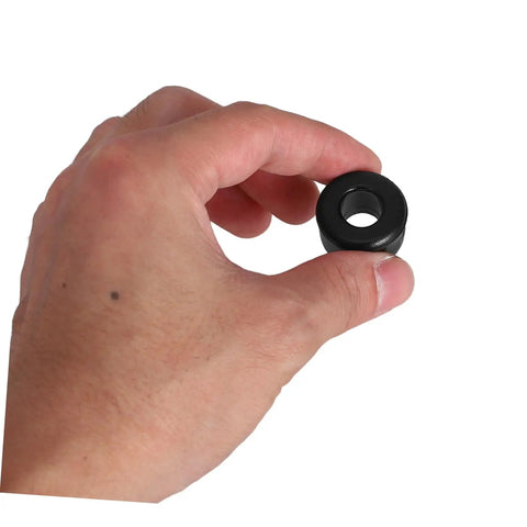 Hand holding a single black PU shock absorbing cushion from the 10 Pack PU Shock Absorbing Cushions for Quad Skates, Beginner Friendly Roller Skating Aid with Double Row Design, Enhanced Stability and Comfort on Concrete and Asphalt, Smooth Ride.