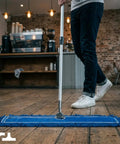 User operating Top Shelf Commercial Dust Mop And Floor Sweeper With Adjustable Handle on hardwood floor in cafe.