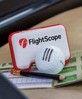 Portable Golf Launch Monitor Mevo With 3D Doppler Radar on table with golf ball, pencil, and scorecard. A real game changer for practice anywhere.