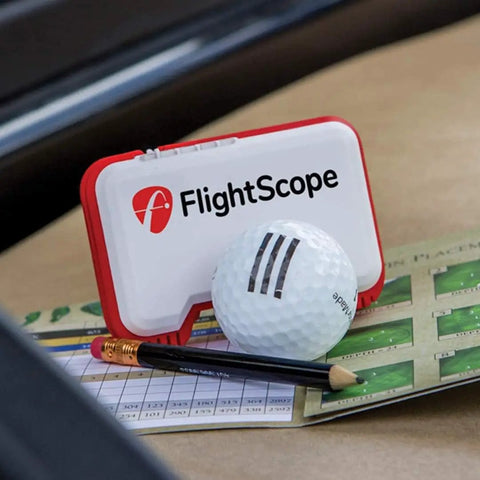 Portable Golf Launch Monitor Mevo With 3D Doppler Radar on table with golf ball, pencil, and scorecard. A real game changer for practice anywhere.