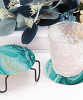 Diamond Art Coaster Set With Holder For DIY Craft Lovers, 8 teal marble coasters with cork pads displayed with a glass on one.