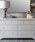 Six Pack Natural Wood Mushroom Cabinet Knobs One Point Five Inch Wide Unfinished drawer handles on gray dresser with lamp and flowers.