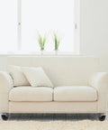 Up Your Game With These Old School Antique Brass Furniture Casters That Roll Like Butter on white sofa with cushions.