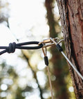 Close-up of a 60Ft Zipline Brake System With Heavy Duty Bungee Cords And Plastic Brake Block attached to a tree in a forest setting.