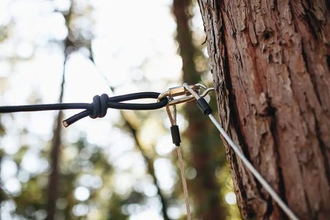 Close-up of a 60Ft Zipline Brake System With Heavy Duty Bungee Cords And Plastic Brake Block attached to a tree in a forest setting.