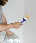 Man holding Pro Grade Adjustable 2.5 Inch Paddle Paint Brush with 270 Degree Angled Flat Tip for Oil and Latex Paint