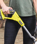 Cordless 18 Volt Patio Surface Cleaner With Telescoping Handle held by a person in a green shirt on a wooden deck.
