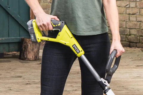 Cordless 18 Volt Patio Surface Cleaner With Telescoping Handle held by a person in a green shirt on a wooden deck.