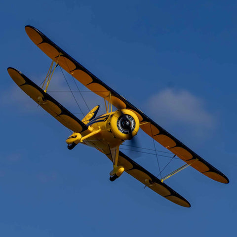 UMX Waco Yellow RC Airplane Bind-N-Fly BNF With AS3X And Safe Technology mid-flight against blue sky.