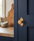 Premium Antique Brass Cabinet Knobs Paired With Elegant Oval Backplates 6 Pack on navy kitchen cabinet door.