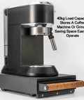 Sturdy Espresso Knocker Drawer And Coffee Knock Box With Shock Absorbing Removable Knock Bar Made From Durable Rubber And Steel To Corral Coffee Grounds Without Mess While Freeing Up Sweet Countertop Real Estate For Hassle Free Daily Shot Pulling Vibes next to a coffee machine.