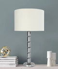 Faceted Metal Floor Lamp With Stacked Column Base, Aged Pewter Finish And Cream Linen Drum Shade in living room setting, Hadley Collection