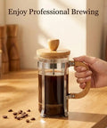 12 Ounce French Press Coffee Maker with Stainless Steel Filter and Borosilicate Carafe, bamboo handle, one cup brew on table