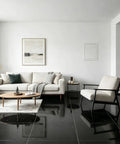 Spacious living room featuring a cozy beige sofa and black tiled floor with wooden coffee table and minimalist decor.