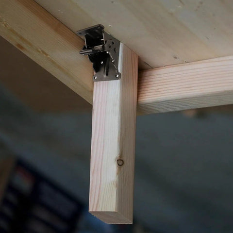Rock Solid Folding Table Leg Brackets With Self Lock Hinges And Screws For Quick Workbench Upgrades Adjustable Zero To Ninety Degrees Bears Up To Five Hundred Pounds In Clean Matte Black attached to a wooden beam.