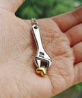 Hand holding Mechanic Wrench Cremation Urn Necklace For Ashes Holder Pendant Spanner Memorial Keepsake For Dad.