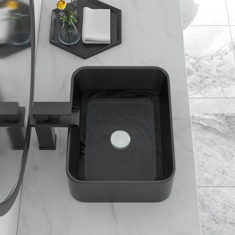 Black rectangular above-counter vessel sink on marble counter in modern bathroom.