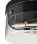 Close-up of 2 Light Flush Mount Ceiling Light in Matte Black with Brass Accents and Clear Glass Shade, bulb sockets visible.