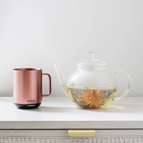 Renewed 6 Oz Smart Heated Coffee Mug With App Precision Temp Control And Solid Battery Life Keeps Your Favorite Brew Piping Hot And Ready For All Day Sipping Sessions next to a glass teapot.