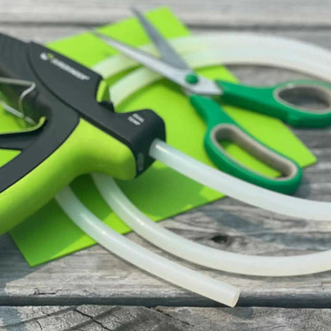Full Size Clear Hot Glue Stick Roll, 5 Feet Long and 0.43 Inch Diameter, shown with green scissors on wooden surface
