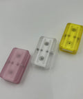 Three Pink Ding Ding Fidget Sliders For Adults, compact PEI gadgets in pink, white, and yellow, ideal for stress relief.